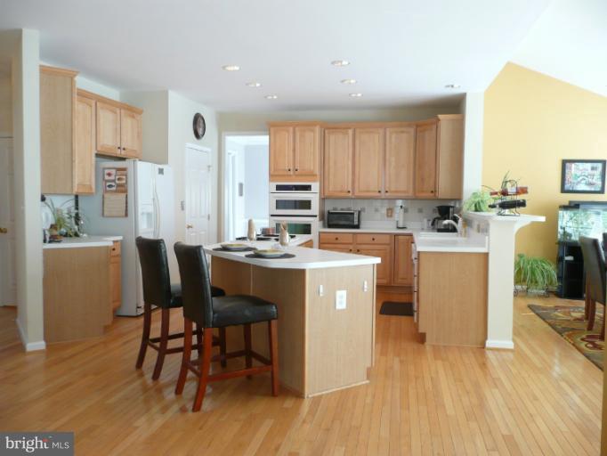 42739 Middle Ridge Place Broadlands, VA 20148 - Photo 6 of 30 a room with stainless steel appliances kitchen island granite countertop a table chairs and a refrigerator