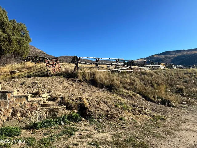a view of a dry yard with wooden fence and mountain