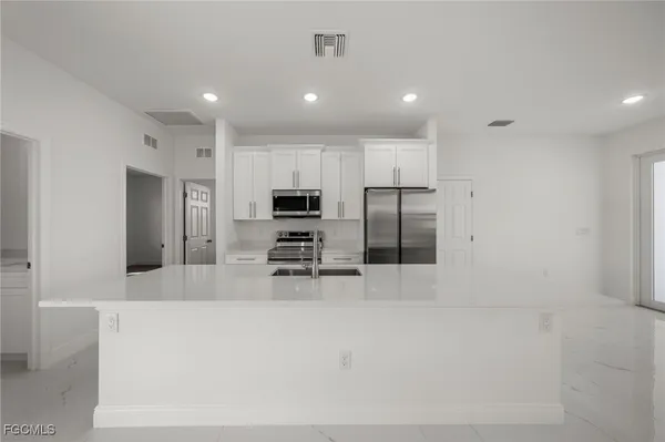 a large kitchen with stainless steel appliances a refrigerator and a stove