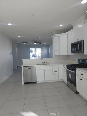 a large kitchen with stainless steel appliances granite countertop a large stove top oven and white cabinets