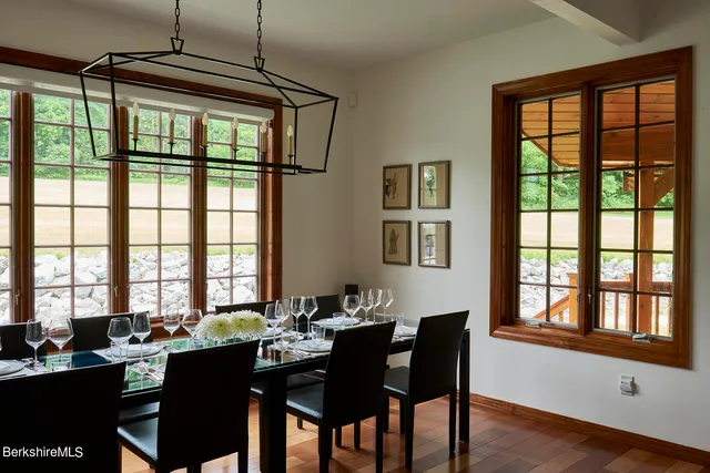 a dining room with wooden floor a chandelier a wooden table and chairs