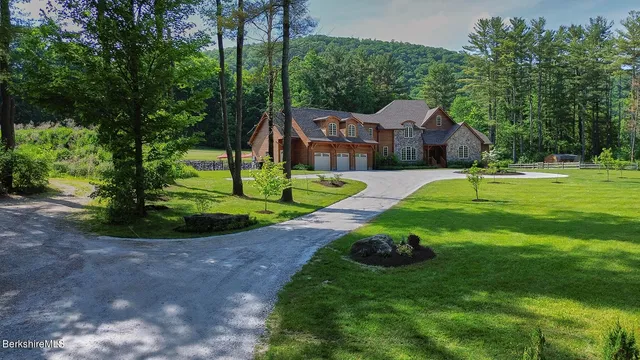 a view of a big house with a big yard and potted plants and large trees