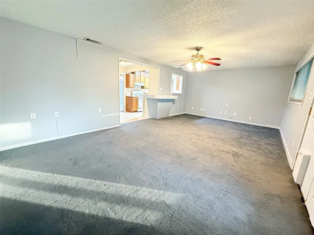 an empty room with windows and ceiling fan