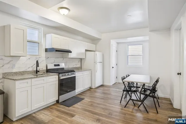 a kitchen with stainless steel appliances granite countertop a white cabinets and wooden floor