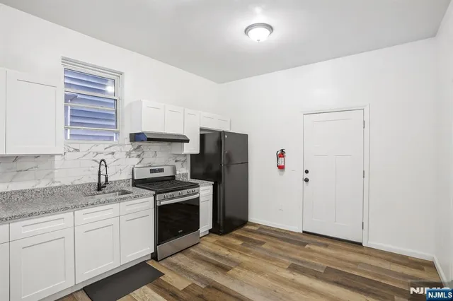 a kitchen with granite countertop a refrigerator stove and sink