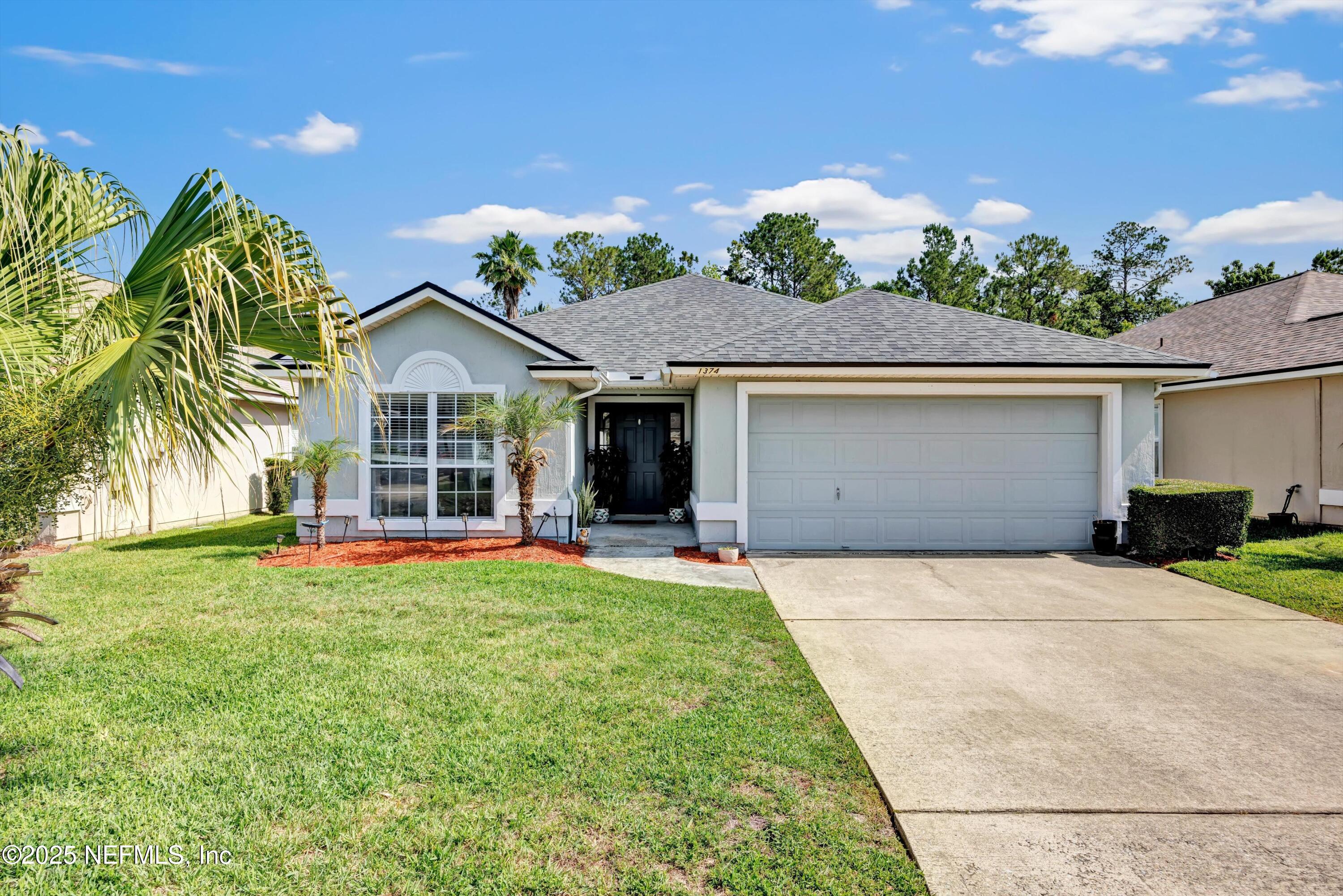 1374 Brookgreen Way Fleming Island, FL 32003 - Photo 2 of 21 a front view of a house with a yard and garage