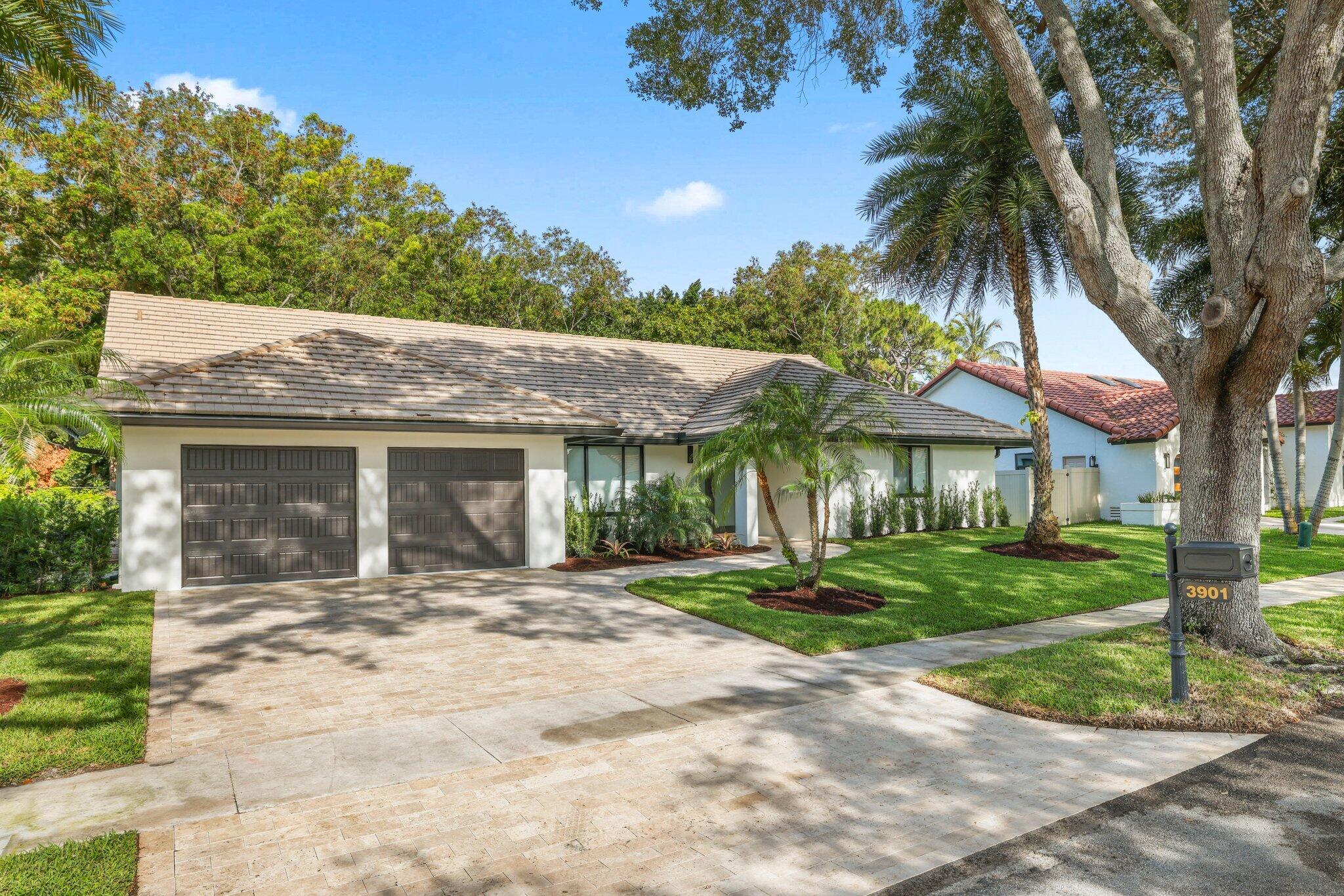 3901 Northwest 27th Avenue Boca Raton, FL 33434 - Photo 3 of 56 a front view of a house with a garden and trees