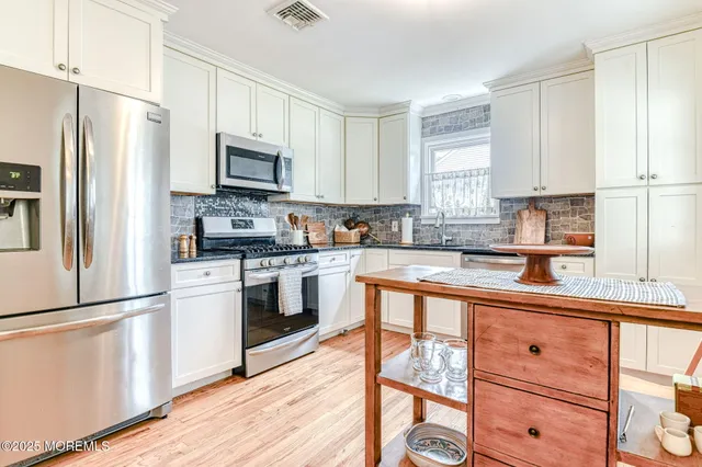 a kitchen with granite countertop white cabinets and stainless steel appliances