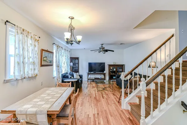 a dining room with wooden floor a chandelier a wooden table and chairs