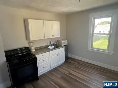 a kitchen with stainless steel appliances a stove a sink and white cabinets