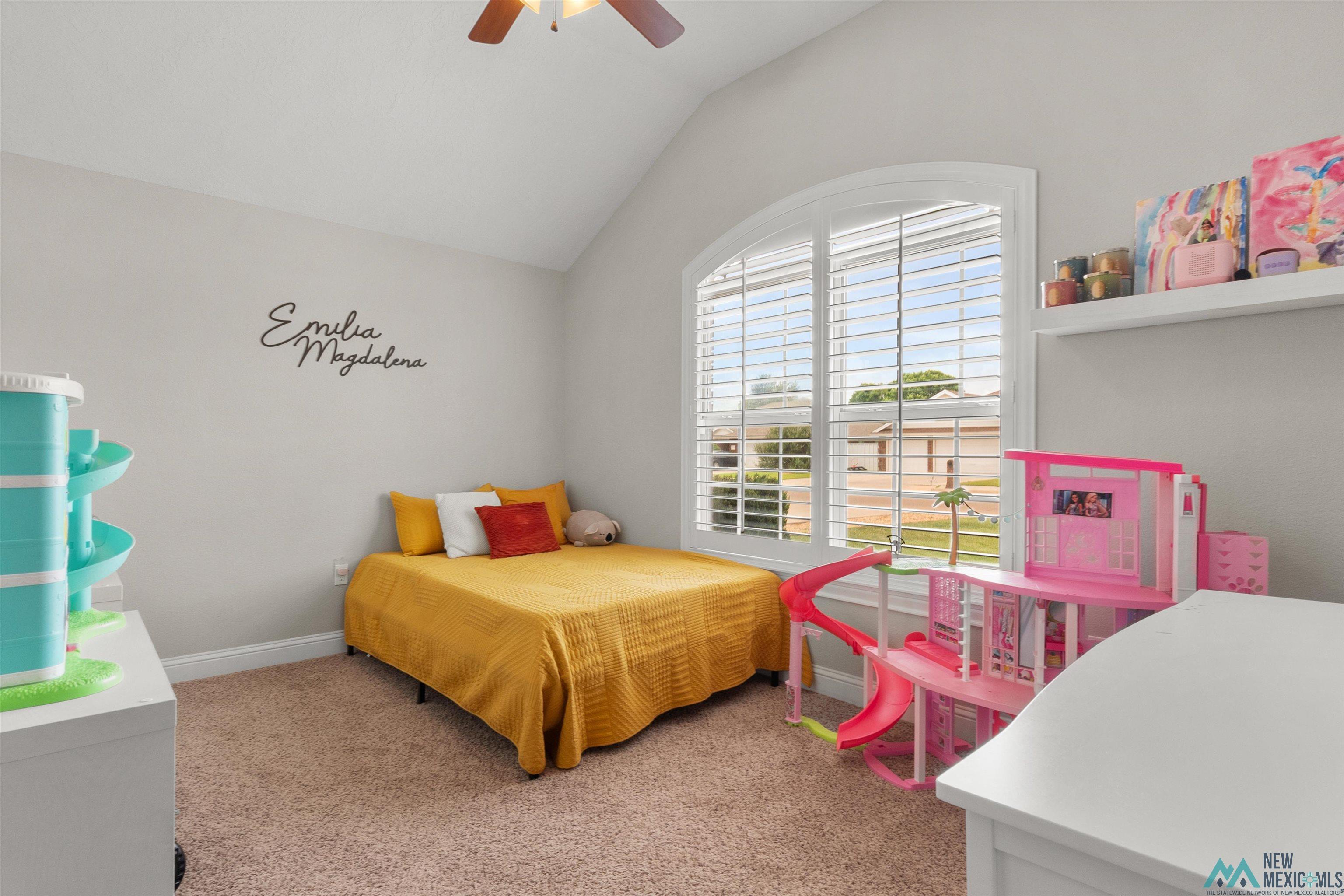 3913 Woodlark Road Clovis, NM 88101 - Photo 22 of 28 Vaulted ceiling bedroom featuring a large arched window with plantation shutters, light gray walls, and carpet flooring