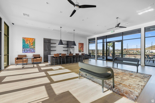 2123 Wolverine Way, Unit 2437 Washington, UT 84780 - Photo 12 of 40 Spacious common area featuring light wood-finish flooring, a full kitchen with dark cabinetry and open shelving, large floor-to-ceiling windows, and multiple ceiling fans
