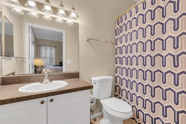a bathroom with a granite countertop sink a toilet and a mirror