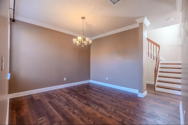 a view of an empty room with wooden floor and stairs