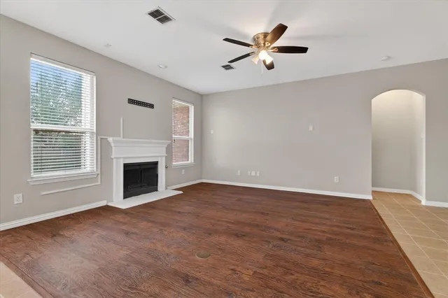 a view of a livingroom with a fireplace a ceiling fan and wooden floor