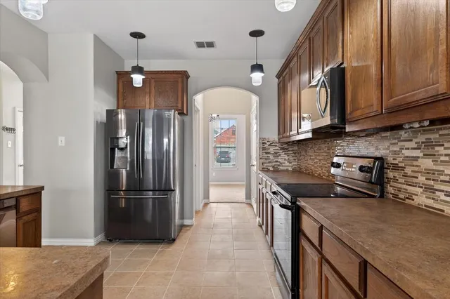 a kitchen with stainless steel appliances granite countertop a refrigerator a stove and a sink