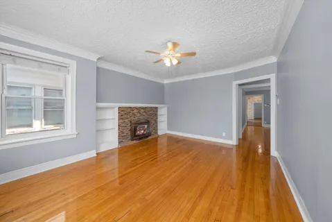 a view of empty room with wooden floor and fan