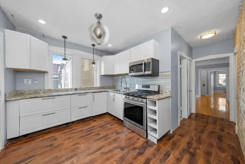 a large kitchen with stainless steel appliances granite countertop a stove and a sink