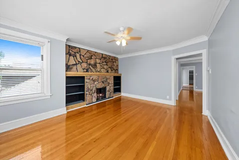 a view of empty room with wooden floor and fan