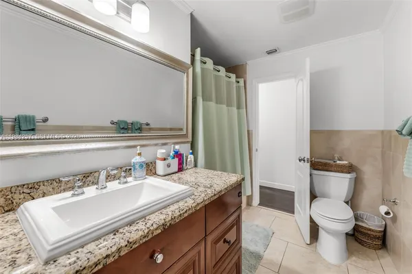 a bathroom with a granite countertop sink a toilet a mirror and shower