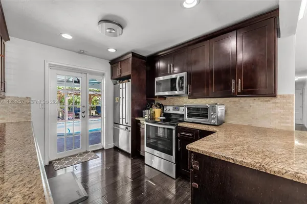 a kitchen with kitchen island granite countertop stainless steel appliances stove microwave and refrigerator