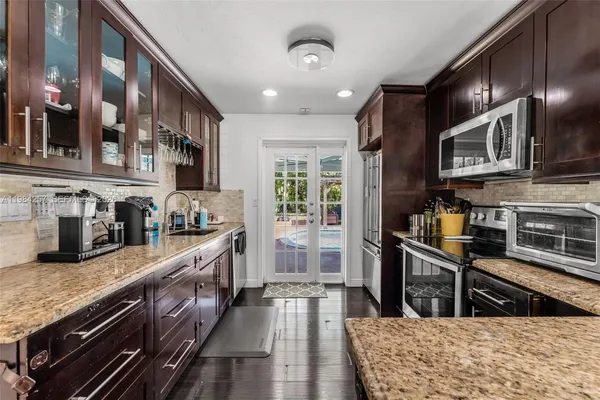 a kitchen with stainless steel appliances granite countertop a refrigerator a stove top oven a sink dishwasher and wooden cabinets with wooden floor