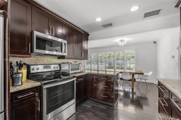 a kitchen with stainless steel appliances a stove a sink a microwave a dining table and chairs