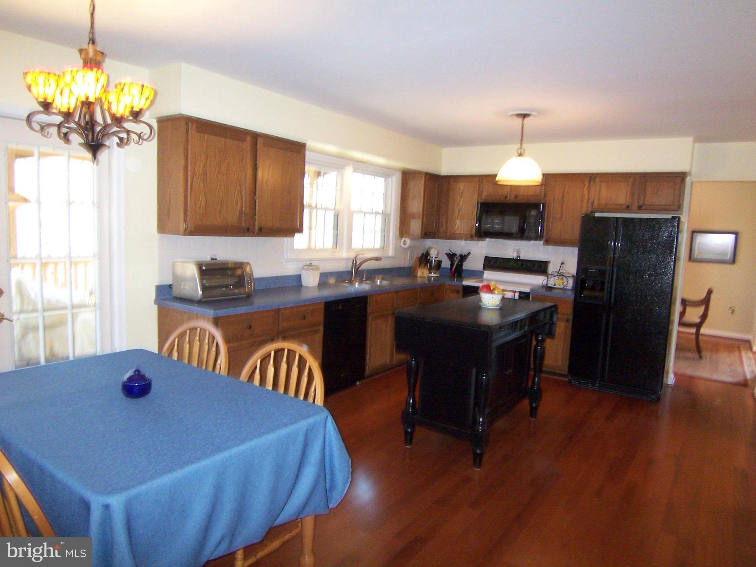 6823 Spring Beauty Court Springfield, VA 22152 - Photo 9 of 29 a kitchen with a refrigerator a sink dishwasher a dining table and chairs with wooden floor