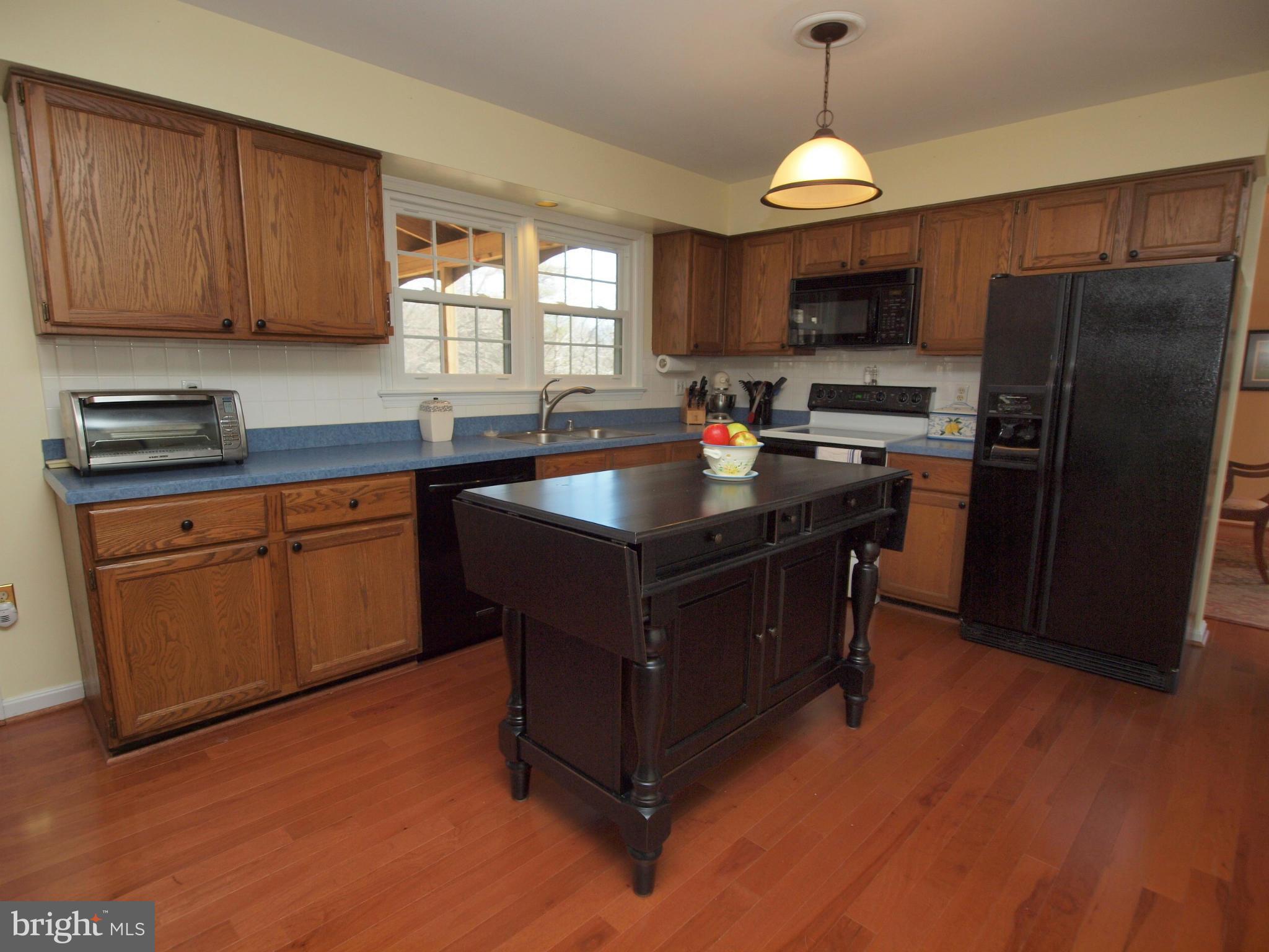 6823 Spring Beauty Court Springfield, VA 22152 - Photo 10 of 29 a kitchen with kitchen island granite countertop a sink dishwasher stove and refrigerator with wooden floor