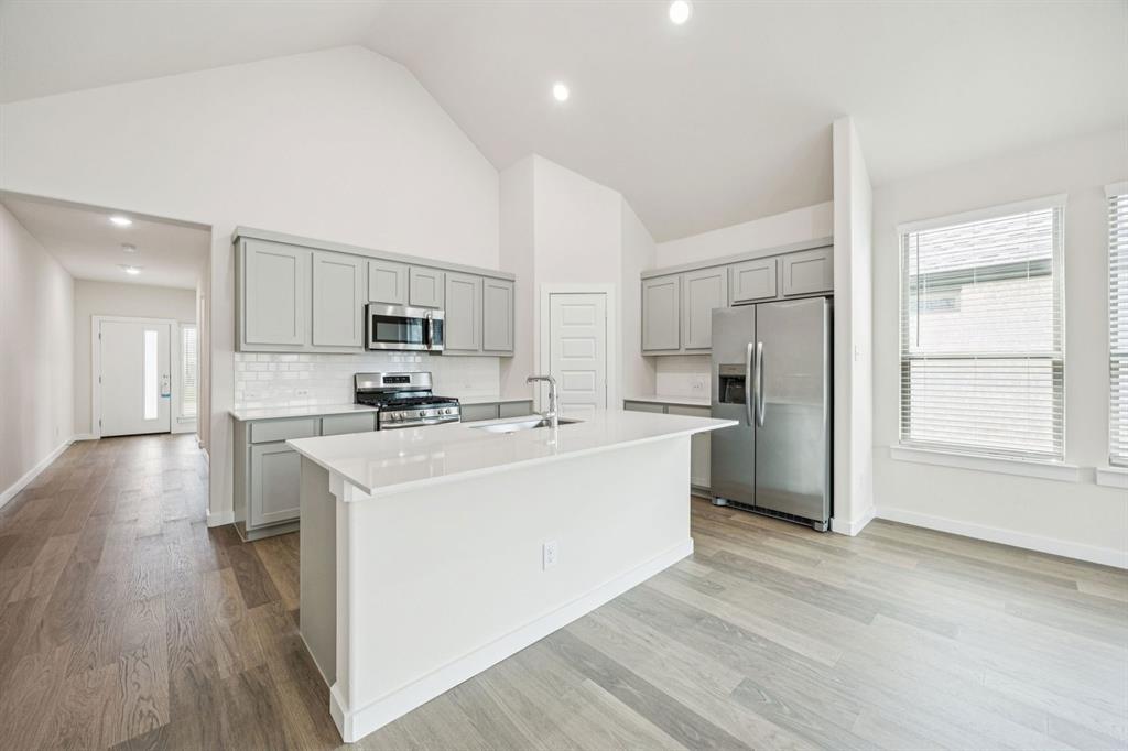 1127 Sunward Road Princeton, TX 75407 - Photo 6 of 29 a kitchen with stainless steel appliances a refrigerator stove a sink and a oven with wooden floor