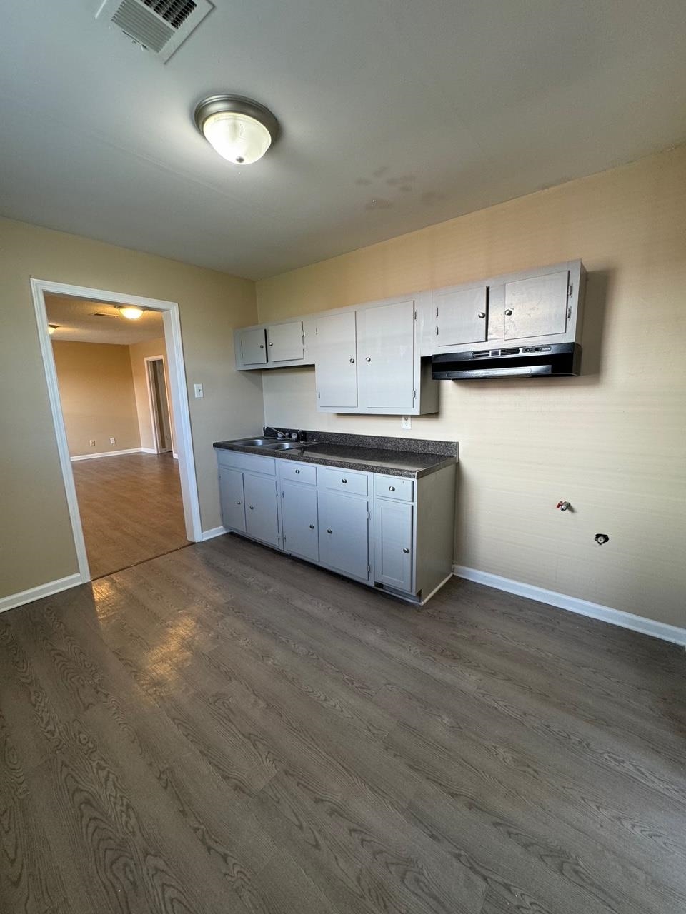 243 West Brooks Road Memphis, TN 38109 - Photo 8 of 19 an empty room with wooden floor and kitchen view
