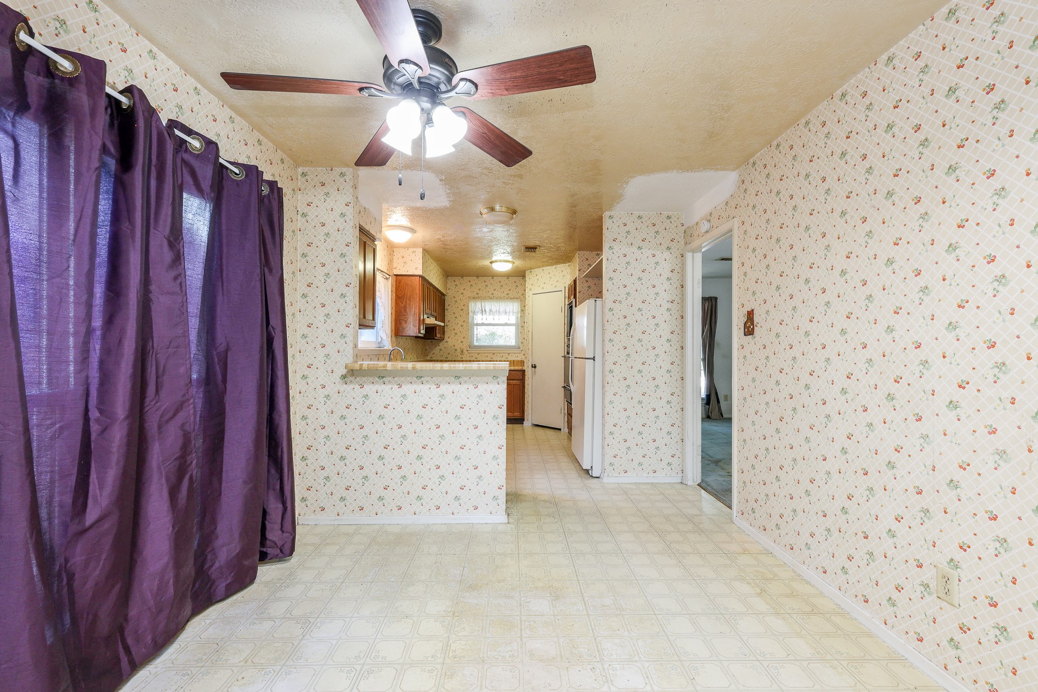 21422 Bridgepoint Lane Spring, TX 77388 - Photo 7 of 20 Breakfast area with floral wallpaper, featuring a ceiling fan and rich purple drapes, seamlessly leading to a kitchen perfect for gatherings.