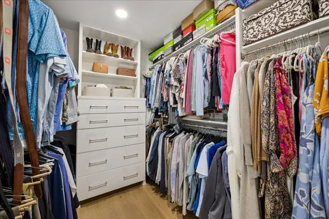 a view of walk in closet with clothes and shoes