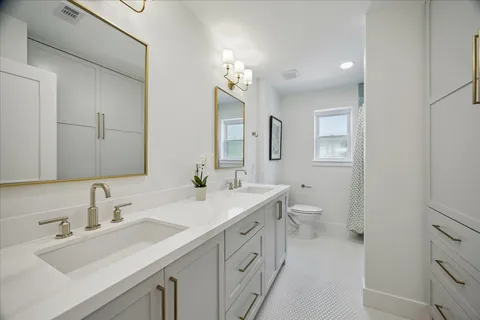 a bathroom with a sink double vanity granite and a toilet