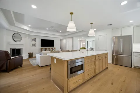 a kitchen with stainless steel appliances granite countertop a stove top oven a refrigerator and a fireplace with wooden floor