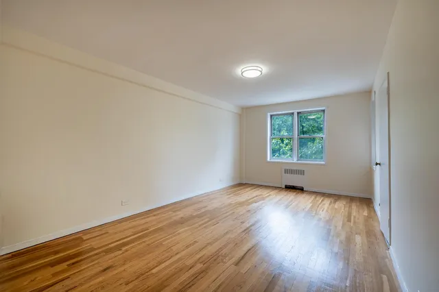an empty room with wooden floor windows and exposed bricks
