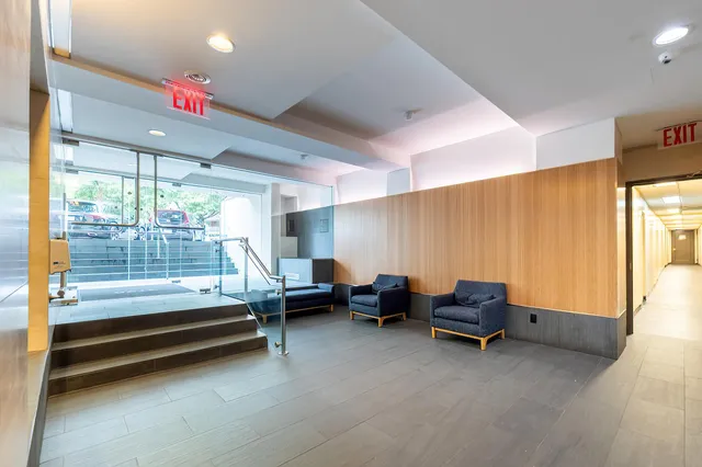 a front view of a building with lot of cars and trees