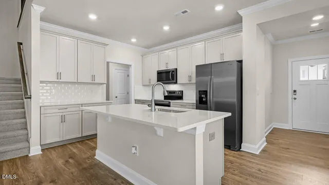 a kitchen with a refrigerator a sink and wooden floor