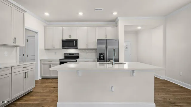 a kitchen with kitchen island a white counter top space stainless steel appliances and cabinets