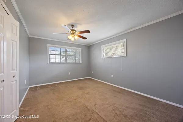an empty room with windows and a chandelier fan