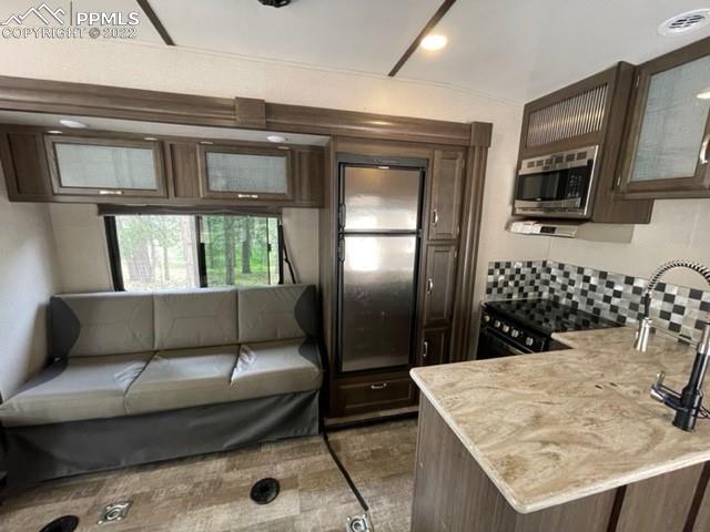34135 Berndt Road Yoder, CO 80864 - Photo 7 of 24 a living room with stainless steel appliances kitchen island granite countertop a refrigerator a stove a microwave oven with white cabinets and wooden floor