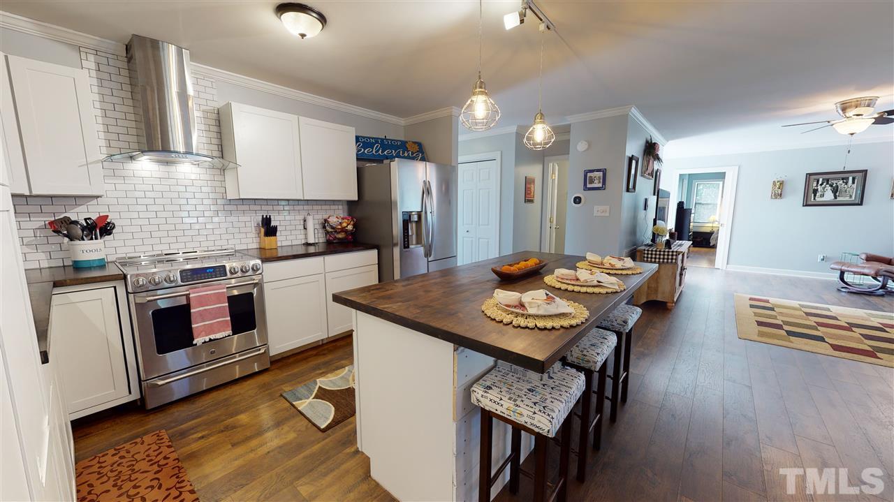 6558 Todd Road Bailey, NC 27807 - Photo 5 of 23 a kitchen with a stove a sink dishwasher a dining table and chairs with wooden floor