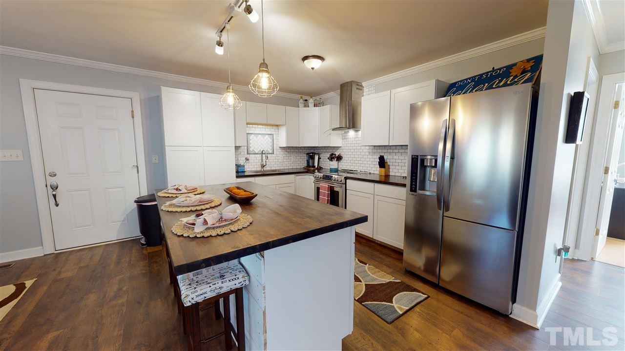 6558 Todd Road Bailey, NC 27807 - Photo 6 of 23 a kitchen with stainless steel appliances granite countertop a refrigerator a sink a stove and white cabinets with wooden floor