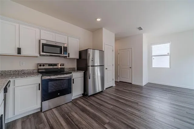 a kitchen with granite countertop a refrigerator and a stove top oven