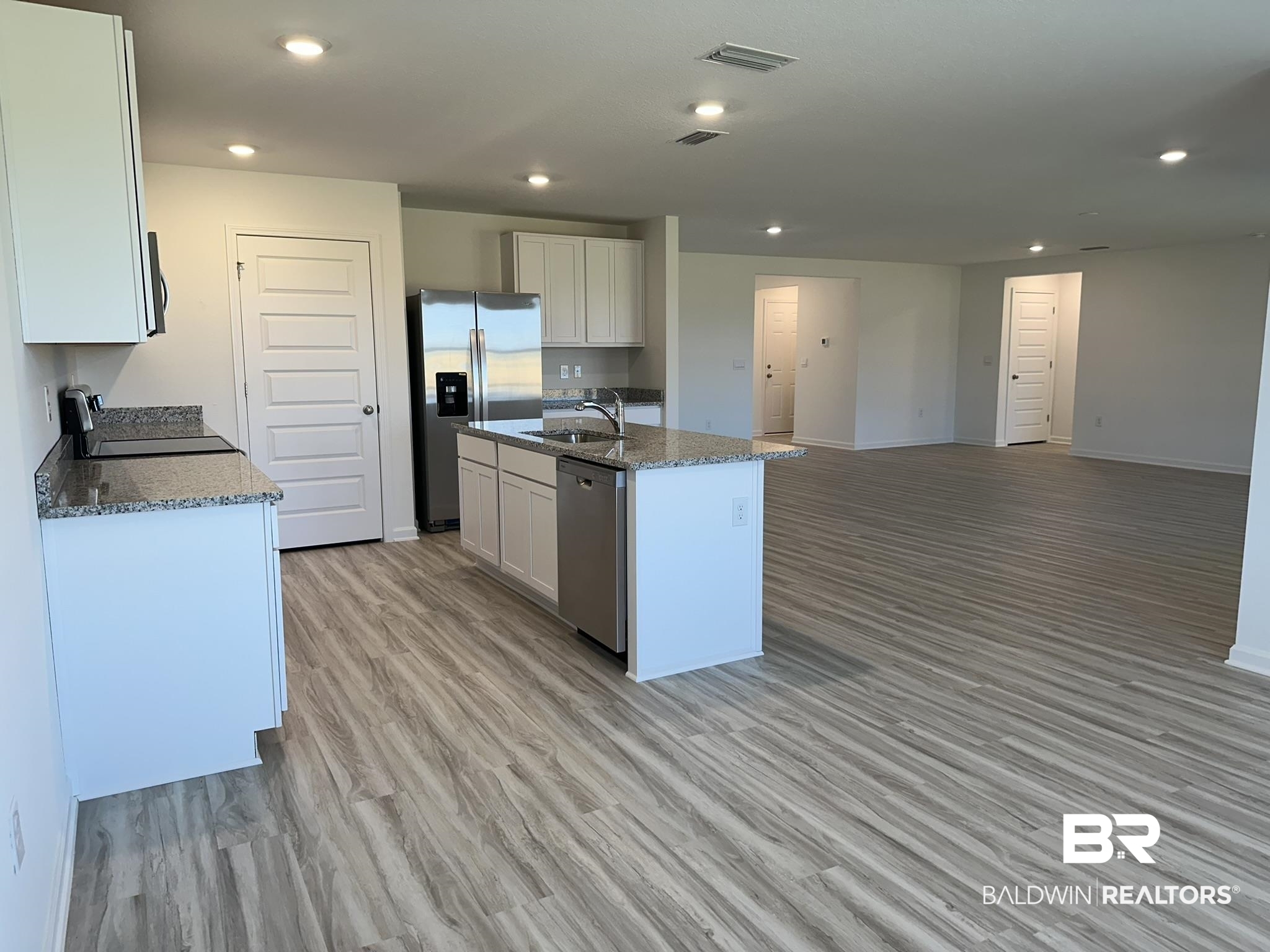 22227 Aleutian Avenue Foley, AL 36535 - Photo 8 of 64 Kitchen with light hardwood / wood-style flooring, sink, an island with sink, white cabinetry, and appliances with stainless steel finishes