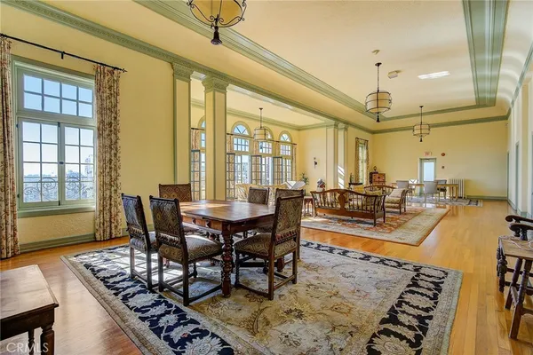 a view of a dining room and livingroom with furniture wooden floor a rug a fireplace and a chandelier