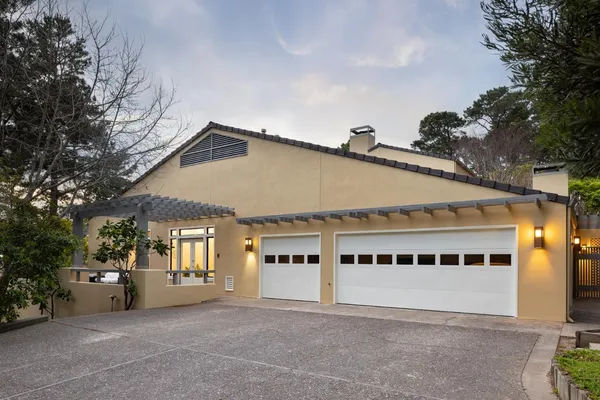 a front view of a house with trees and plants