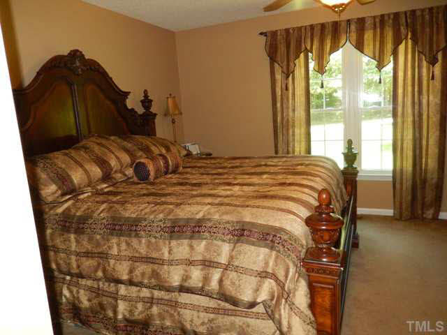 3151 Sanders Road Willow Spring, NC 27592 - Photo 16 of 24 a bed sitting in a bedroom next to a window