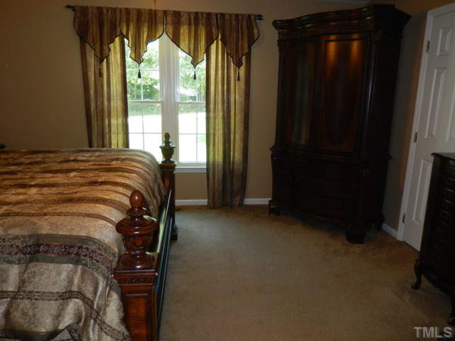 3151 Sanders Road Willow Spring, NC 27592 - Photo 17 of 24 a bed sitting in a bedroom next to a window