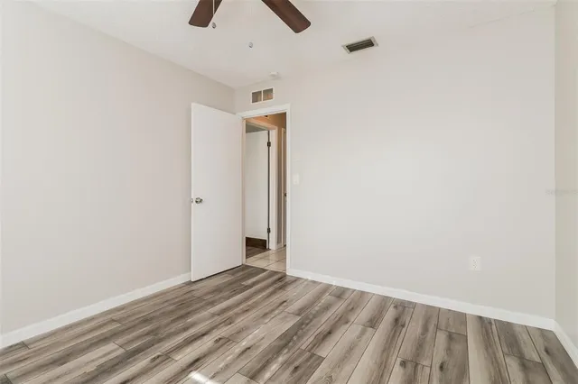 an empty room with wooden floor cabinet and windows